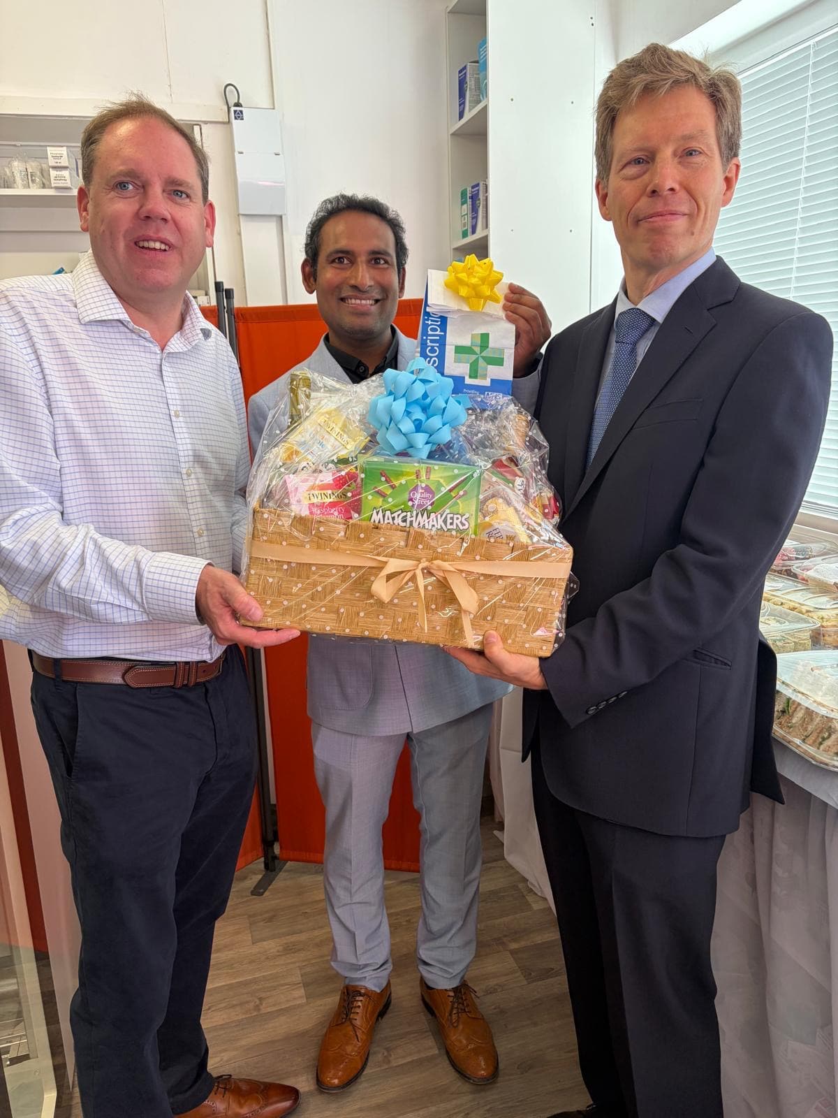 Charlie Dewhirst MP, Jaya Gaali and Prince Alexander von Liechtenstein holding a celebratory hamper at Marton Road Pharmacy